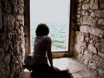 Rear view of girl standing against window