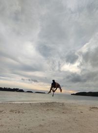 Man running on beach against sky