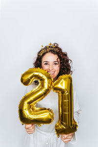 Portrait of smiling woman holding balloons against white background