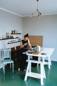 Woman using mobile phone while standing at home