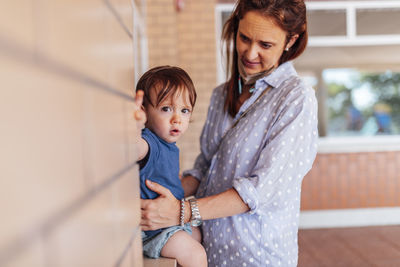 Portrait of son with mother sitting by wall