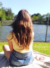 Rear view of girl looking at lake against sky