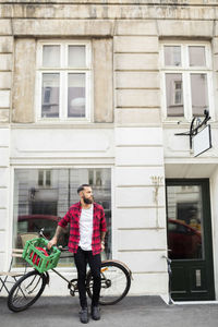 Owner with bicycle on sidewalk outside candy store