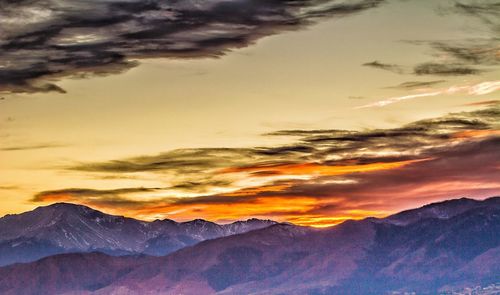 Scenic view of dramatic sky over mountains during sunset