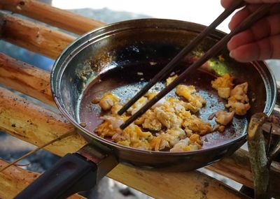 Close-up of hand holding food in bowl on table