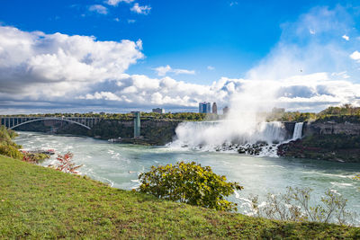 Scenic view of waterfall against cloudy sky