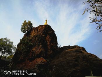 Low angle view of rock formation on cliff against sky