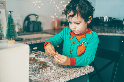 In a cozy kitchen, a happy mom and her son bond over christmas gingerbread preparation