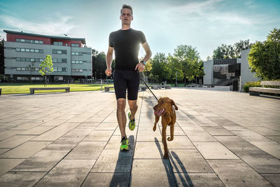 Rear view of man with dog walking on footpath