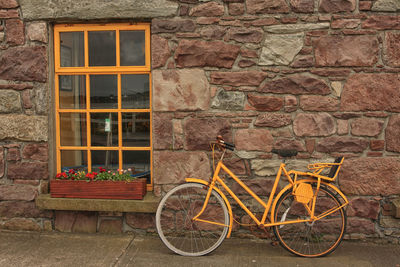 Bicycle parked against brick wall