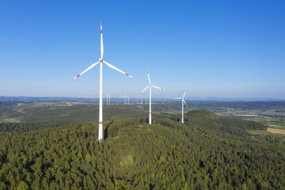 Wind turbines on field against sky