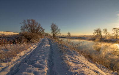 Snow covered field against sky during winter