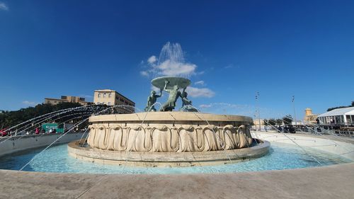 Statue of fountain in city against blue sky