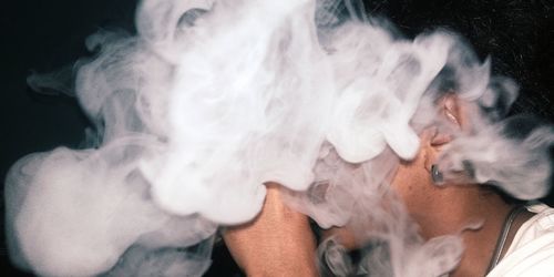 Close-up of man smoking against black background