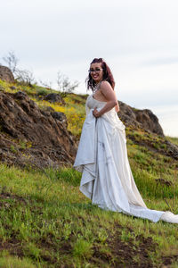 Young woman standing on mountain against sky
