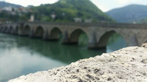 Close-up of retaining wall against arch bridge over river