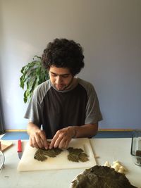 Young man looking away while sitting on table at home