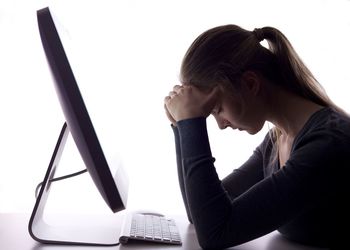 Side view of stressed businesswoman sitting by computer against white background