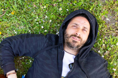 Hippy man lying down with beard and headphones outdoors on the grass