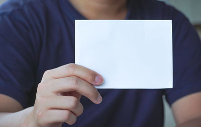 Midsection of man holding paper with text