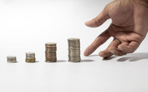 Close-up of hand holding stack over white background