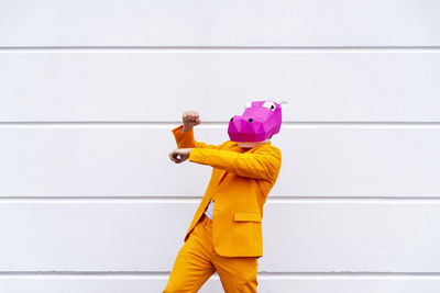 Side view of man standing against yellow wall