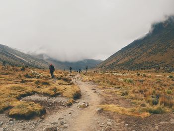 Rear view of man on field by mountains against sky