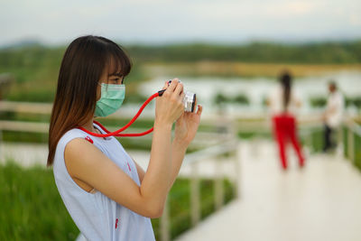 Side view of woman holding mobile phone outdoors