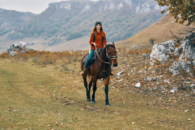 Young woman riding horse on field