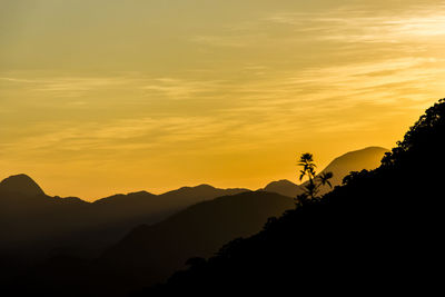 Scenic view of silhouette mountains against orange sky