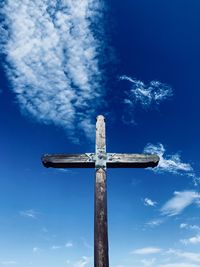 Low angle view of cross on wooden post against sky