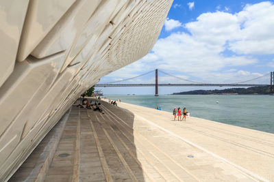 People on bridge over sea against sky