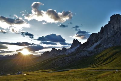 Scenic view of landscape against cloudy sky during sunny day