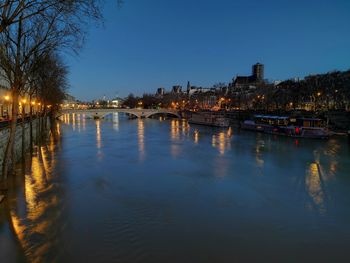 River by illuminated city against clear sky at night