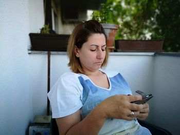Mature woman using smart phone while sitting outdoors