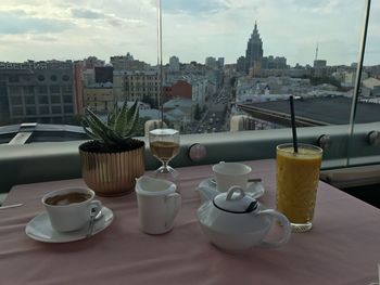 Coffee cup and buildings on table against sky in city