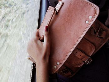 Close-up of hand holding leather bag