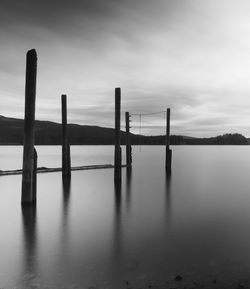 Wooden posts in lake against sky