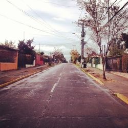 Empty road along bare trees