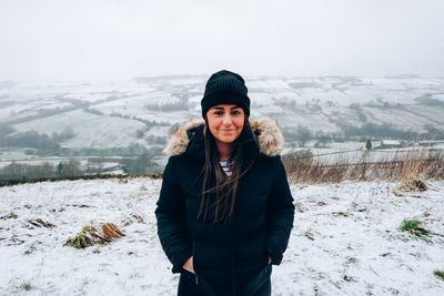Portrait of smiling young woman standing on snow field