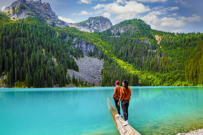 Rear view of woman standing by lake