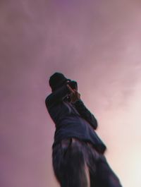 Low angle view of person holding bird against sky