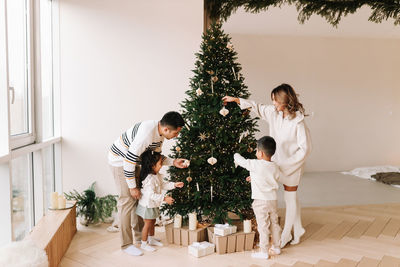 An asian multi-racial family with two children celebrate the christmas in a decorated indoor house