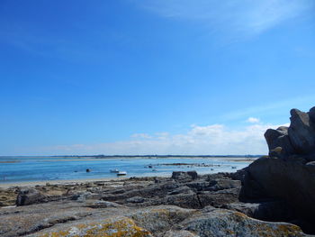 Rock by seascape against blue sky