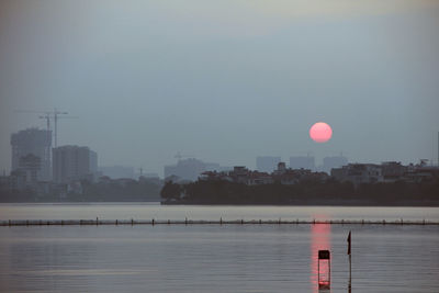 Scenic view of lake against sky in city