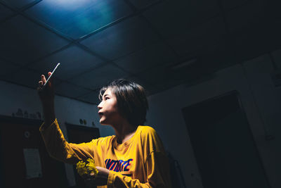 Side view of young woman taking selfie in darkroom