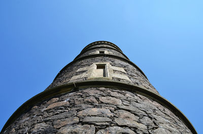 Low angle view of old tower against clear blue sky