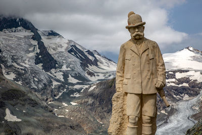 Statue on snow covered mountain against sky