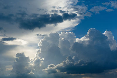 Low angle view of sunlight streaming through clouds