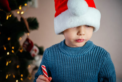Little boy in santa hat eating candy cane lollipop lo at christmas time